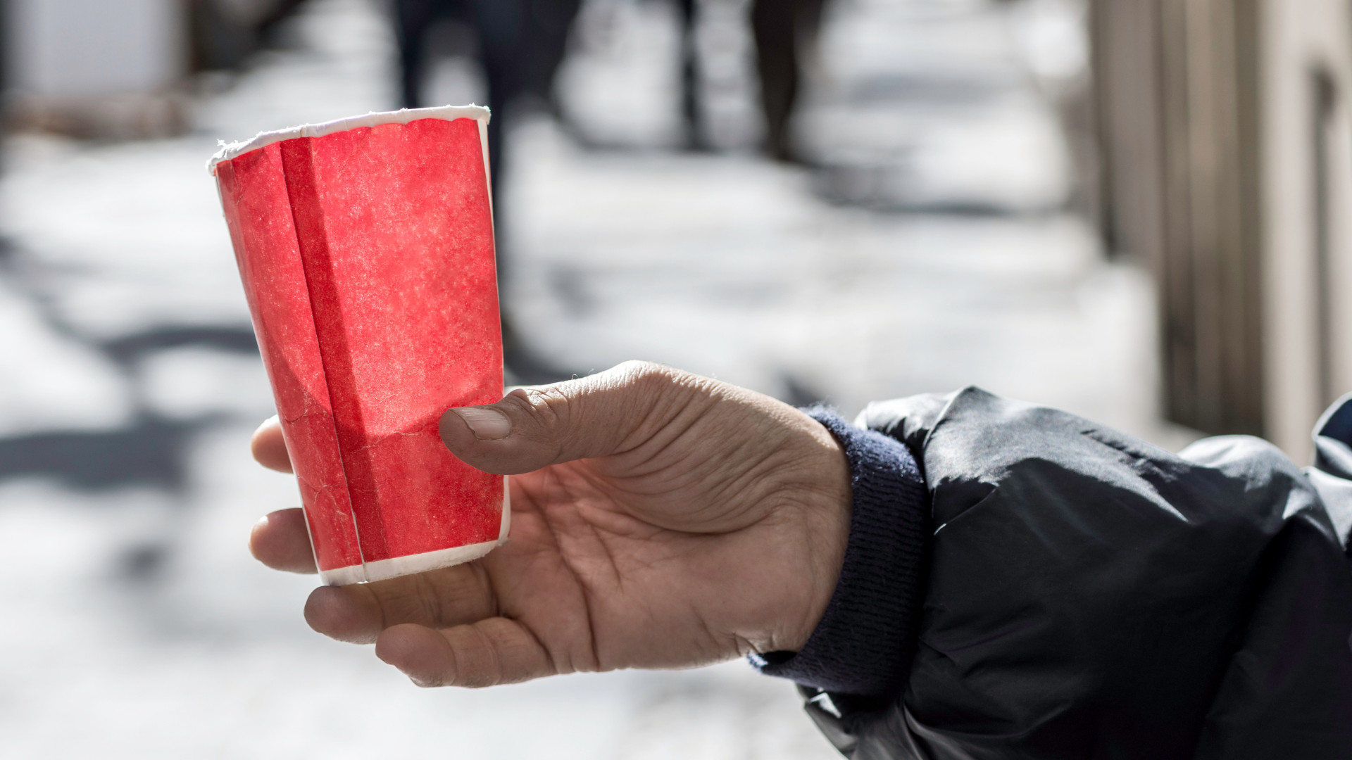 Um Geld bettelnde Person ausgestreckte Hand, die Pappbecher hält