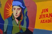 Jin Jiyan Azadi: kurdisch für Women, Life, Freedom / Frauen, Leben, Freiheit. Wandmalerei der Improper Walls in der Schwendergasse in Rudolfsheim-Fünfhaus, Wien. Kurdische Frauenkombatantin von der Künstlerin Btoy nach einem Foto von Maryam Ashrafi