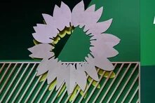 Foto: Ein abstraktes Wandbild mit einer stilisierten Sonnenblume. Es sind große, unregelmäßige Blütenblätter in Holzoptik und gelben Akzenten zu sehen.