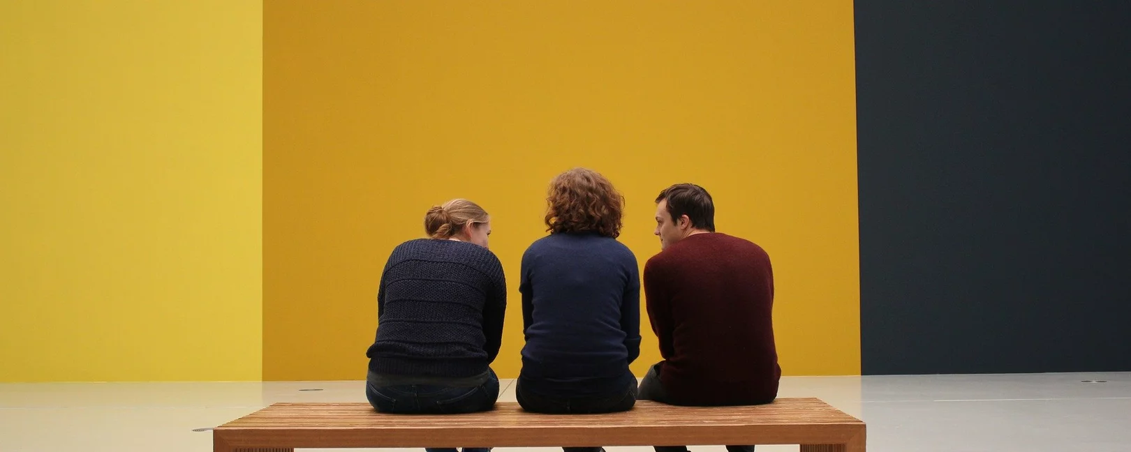 Drei Menschen auf einer Bank in einer Ausstellung