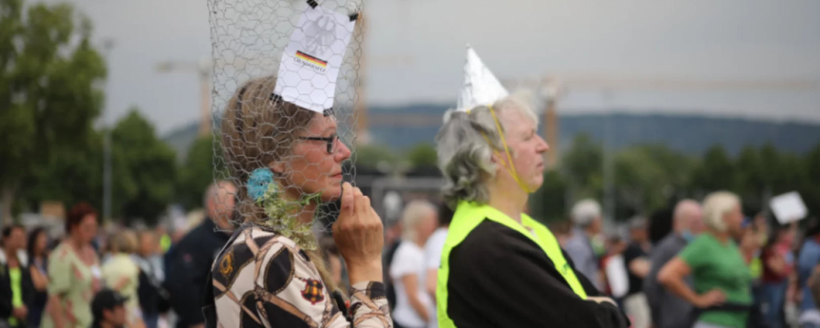 Participants take part in a demonstration against Coronavirus restrictions in Stuttgart, Germany on May 9, 2020. Similar protests and actions are being held worldwide with people asking for freedom of movement and religious ceremonies. One Person is wearing an aluminium hat, another is wearing a metal net around her head with the constiution on it.