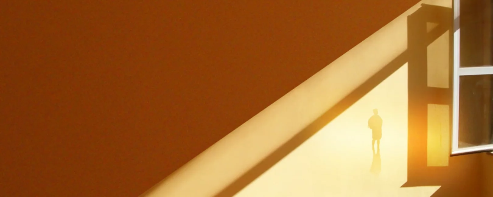 geöffnetes Fenster mit einstrahlender Sonne, im Licht steht eine Person