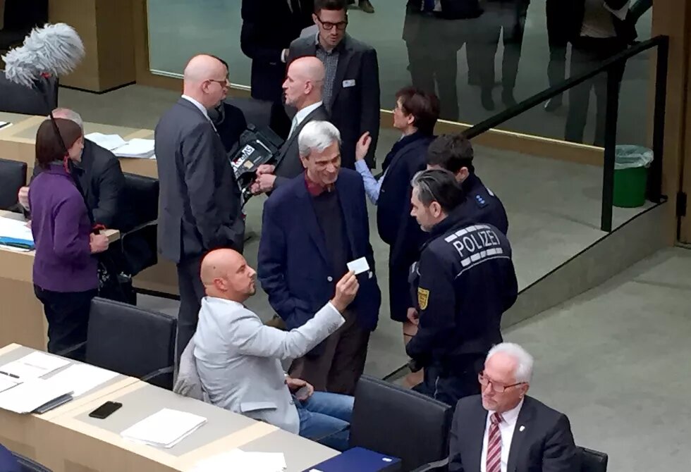 12.12.2018, Baden-Württemberg, Stuttgart: Stefan Räpple (sitzend, l), Abgeordneter der AfD im Landtag von Baden-Württemberg, spricht während einer Plenarsitzung mit Polizisten. Zuvor hatte er sich geweigert, trotz Aufforderung der Landtagspräsidentin, den Saal zu verlassen. In der Mitte steht der fraktionslose Landtagsabgeordnete und AfD-Politiker, Wolfgang Gedeon, (zu dpa: "Polizei-Einsatz im Plenum - Landtagssitzung wegen Räpple unterbrochen" vom 12.12.2018) - Bestmögliche Qualität - Foto: Nico Pointner/d